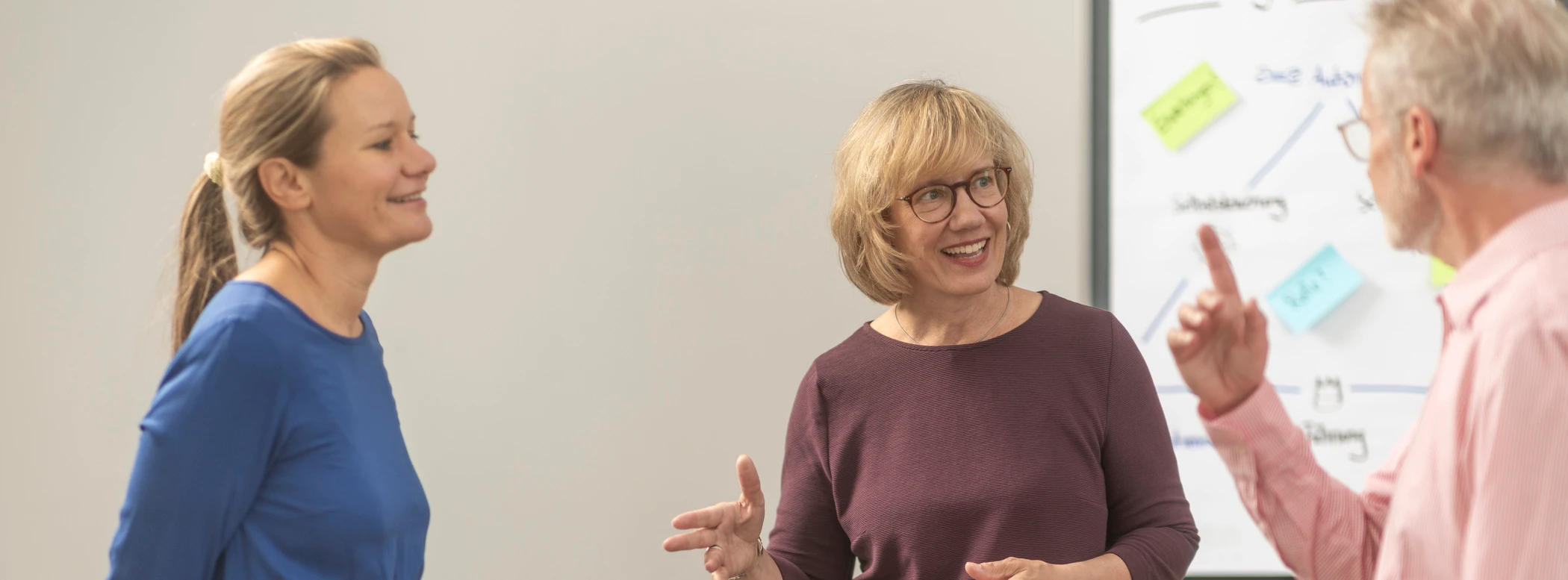 Drei Personen in einem Coaching vor einem Whiteboard