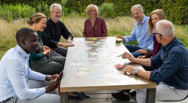 Gruppe sitzt an einem Tisch während dem Teamcoaching